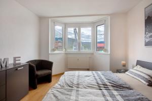 een slaapkamer met een bed, een stoel en ramen bij Haus Castellbergblick mit Balkon in Ballrechten