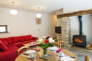 a living room with a red couch and a wood stove at La grange aux roses in Nojaret