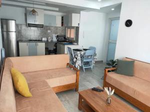 a living room with a couch and a kitchen at Apprt Proche Plage - Bien equipé in Kelibia