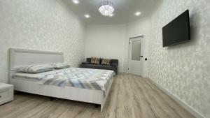 a bedroom with a bed and a flat screen tv at Уютная 1-ком кв в Жк Альтаир мкр Батыс-2 in Aktobe