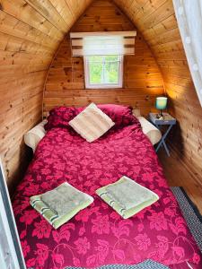 a bedroom with a red bed in a wooden cabin at Yule Tree Campsite in Helston