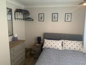 een slaapkamer met een bed, een ladekast en een spiegel bij Barley Break - Beach Cottage in Lessingham