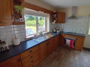 a kitchen with wooden cabinets and a sink and a window at Ash Lodge Leitrim Village in Leitrim