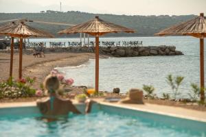 a woman sitting in a swimming pool next to a beach at Terra Park Phalaris in Novalja