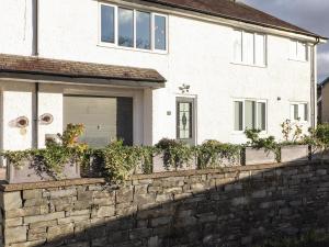 a white house with a stone retaining wall at Tipsy Bee in Windermere