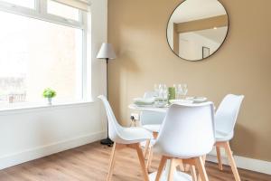 a dining room table with white chairs and a mirror at Moncrieff House in Livingston