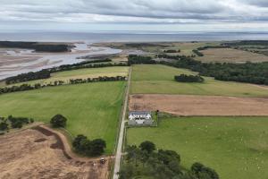 an aerial view of a house in a field next to a river at Balvraid Steading - Awesome views, near Dornoch in Dornoch +2 photos