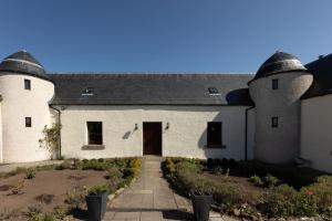 a white building with a black roof and a driveway at Balvraid Steading - Awesome views, near Dornoch in Dornoch