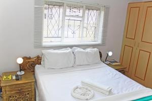 a white bed with white pillows and a window at BGH LODGE in Gaborone