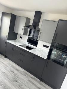 a kitchen with black and white counters and appliances at Modern 3 Bedroom Apartment in Millerhill