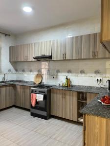 a kitchen with wooden cabinets and a black stove top oven at Live Well Rwanda House in Kigali