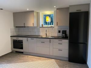 eine Küche mit weißen Schränken und einem schwarzen Kühlschrank in der Unterkunft Solbergshyllan 2 in Åre
