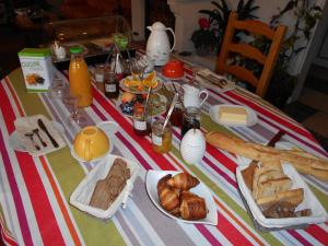 a table with bread and pastries and bottles of orange juice at Les Tilleuls B&B in Orange