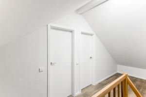 a room with white cabinets and a staircase at Vila Naktižiedė in Šventoji +1 photo