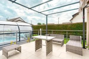 un patio avec une table et des chaises sur un balcon dans l'établissement Villa confortable à Ranville, piscine privée, à Ranville