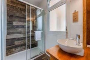 a bathroom with a sink and a glass shower at Hôtel Le Grain de Sable in Arès