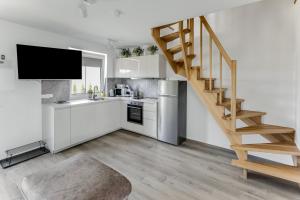a kitchen with white cabinets and a wooden staircase at Vila Naktižiedė in Šventoji