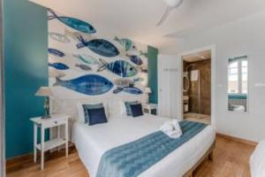 a bedroom with a bed and a mural of fishes at Hôtel Le Grain de Sable in Arès