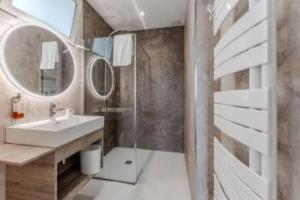 a bathroom with a sink and a mirror at Hôtel Le Grain de Sable in Arès