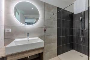 a bathroom with a sink and a mirror and a shower at Hôtel Le Grain de Sable in Arès