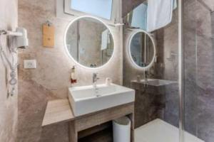 a bathroom with a sink and two mirrors at Hôtel Le Grain de Sable in Arès