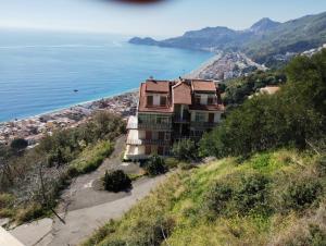 a building on a hill next to the ocean at Don Vladi in Letojanni