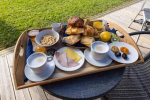 a tray of food on a table with cups of coffee at Hôtel Le Grain de Sable in Arès