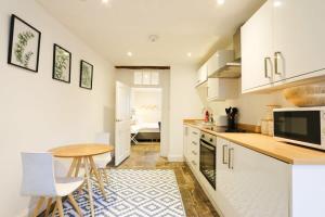 a kitchen with white cabinets and a table and chairs at Spacious Boutique Apartment Clifton King Size Bed in Bristol