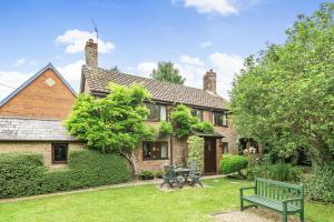 a house with a green bench in the yard at Chapel Cottage in Winterborne Kingston