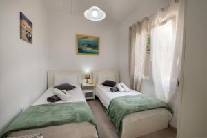 two beds in a room with a window at Loggos Seaview Cottage with Private Pool by Konnect in Longos
