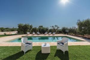 a pool with chairs and a table in the grass at Domus Petri 1908 in Cisternino