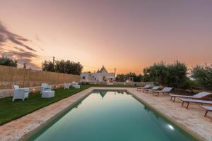 a pool with lounge chairs and a building in the background at Domus Petri 1908 in Cisternino