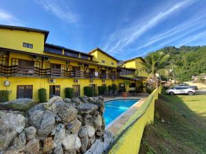 a building with a swimming pool in front of a house at Pousada Azul Banana - Maresias in Maresias