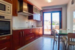 una cucina con armadi in legno, un tavolo e una sala da pranzo di Luma, apartamento con terraza a Cambados