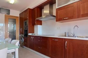 una cucina con mobili in legno, un lavello e una stufa di Luma, apartamento con terraza a Cambados Altre 8 foto