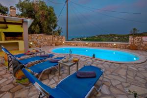 a swimming pool with blue lounge chairs and a table at Loggos Seaview Cottage with Private Pool by Konnect in Longos