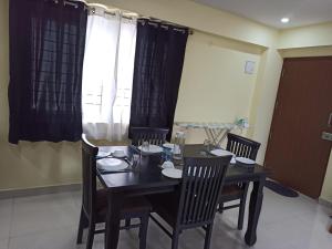 a dining room with a table and chairs and a window at Soma Peaceside accommodation services in Bangalore