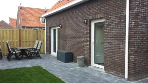 a patio with a table and chairs next to a brick building at Holiday Home D'arke in Westkapelle