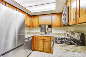 ソルトレイクシティにあるCozy and Centrally Located SLC Condo with Balcony!のキッチン(木製キャビネット、ステンレス製の冷蔵庫付)
