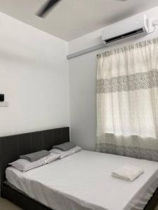 a bed in a room with a window with white sheets at Homestay73 - Parit Raja in Parit Raja