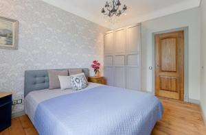 a bedroom with a large bed and a chandelier at Quiet garden deluxe apartment in Rīga