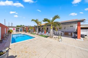 a swimming pool with palm trees and a building at Ierlandstraat 23 in Oranjestad