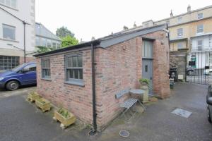 a brick building with a table and a bench in a parking lot at The Coach House, Clifton and Parking - Hopewell in Bristol