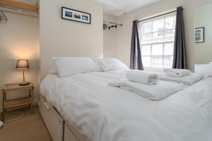 a large white bed in a room with a window at Super central cosy & cute North Laine cottage in Brighton & Hove