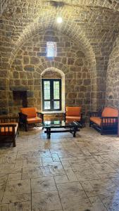 Una habitación con sillas y una chimenea en una pared de piedra. en Bayt Al Habib, 