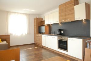 a kitchen with white cabinets and wood floors at Appartament Eichnerhof in Chienes