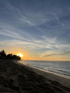 a sunset on a beach with the ocean at Akule Clubhouse- Awa 1 Bedroom Apt by the Beach condo in Waialua +16 photos