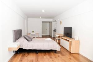 ein Schlafzimmer mit einem Bett, einem Schreibtisch und einem Fernseher in der Unterkunft Belgrano amplio luminoso, cochera, WiFi, cerca River y Subte, 309 in Buenos Aires