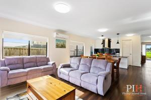 a living room with two purple couches and a kitchen at Recently build 4BDR Family Home in Quiet Estate in Cowes