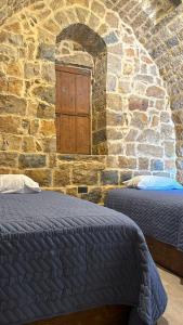 Habitación con 2 camas frente a una pared de piedra. en Bayt Al Habib, 